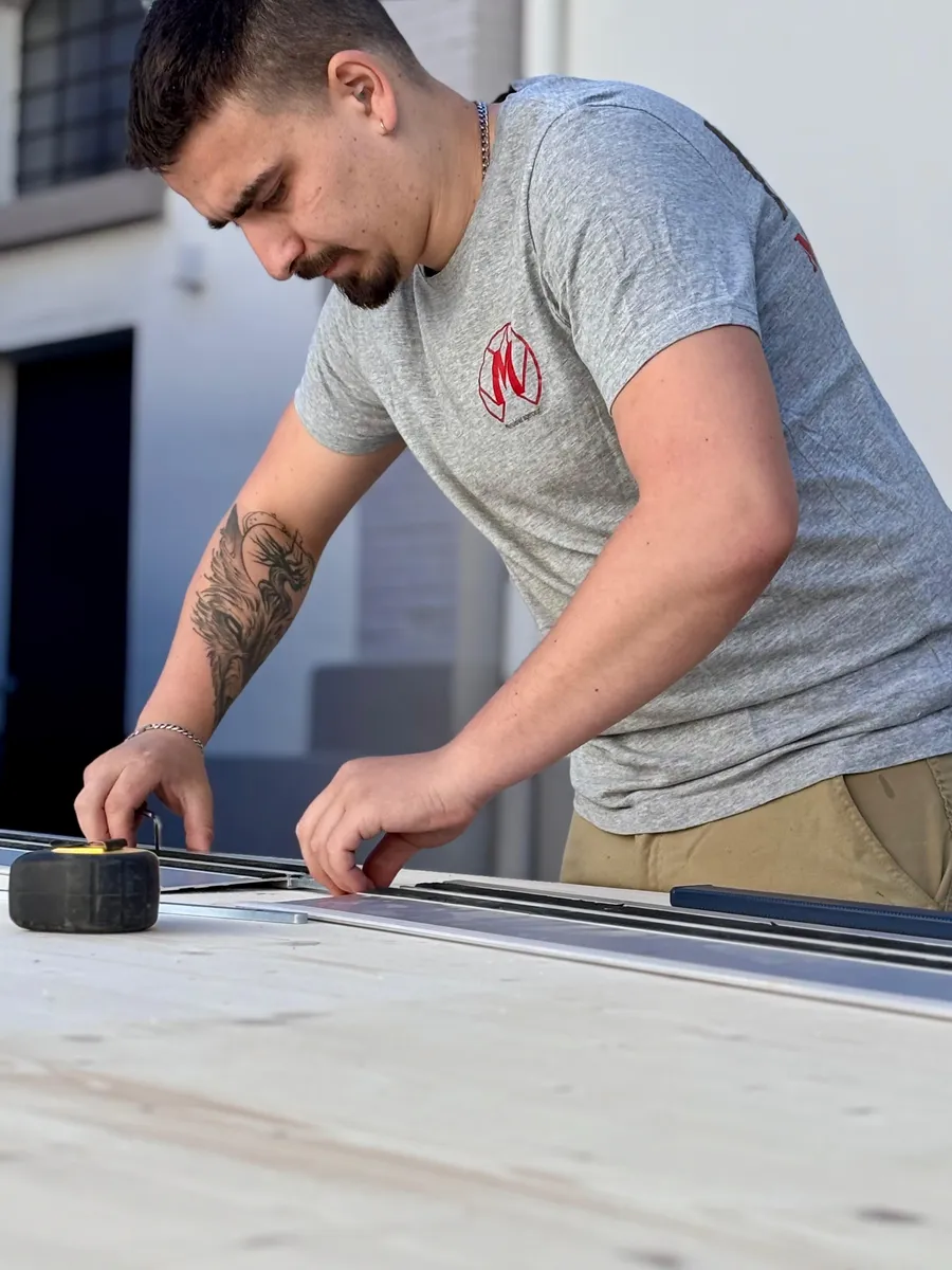 Hugo Di Murro, artisan menuisier HDM Menuiserie, mesurant une planche à l'atelier de Givors