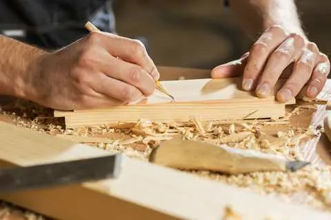 Artisan menuisier traçant une pièce en bois dans l'atelier HDM à Givors